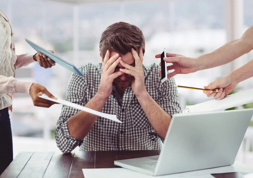 Homem estressado no trabalho ao receber diversas cobranças