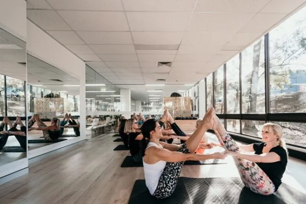 Turma feminina de pilates realizando movimento em dupla