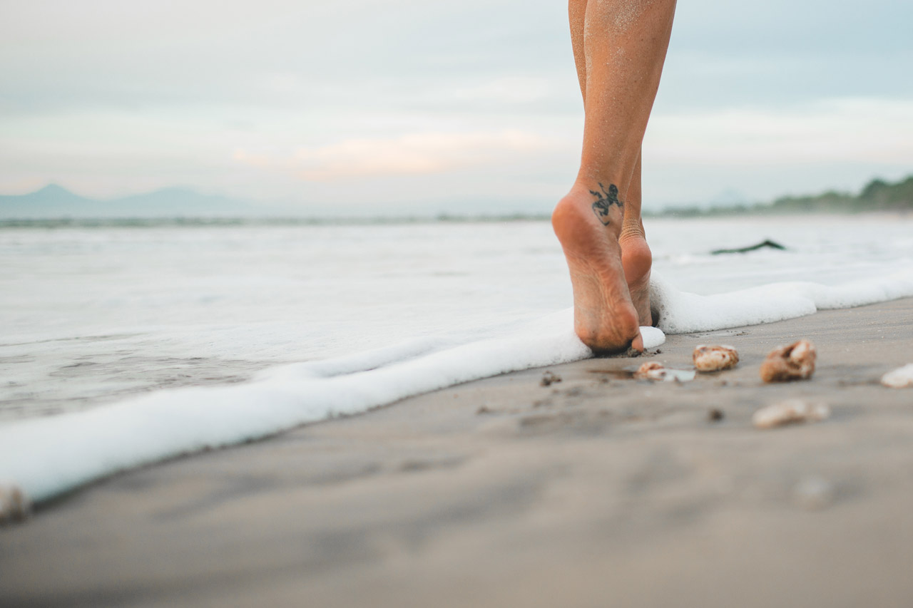 Mulher andando descalça na praia