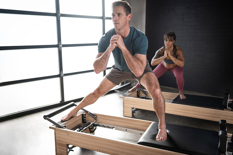 Homem e mulher em um aparelho reformer de pilates