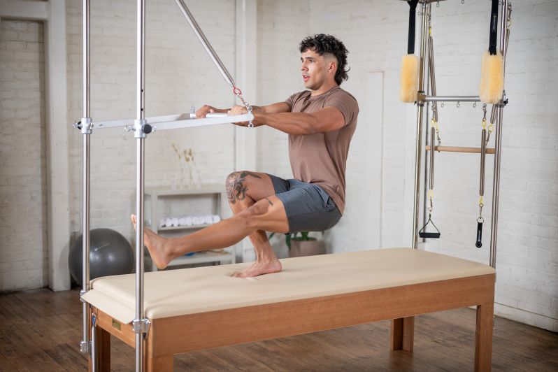 homem fazerndo exercicio de pilates no aparelho