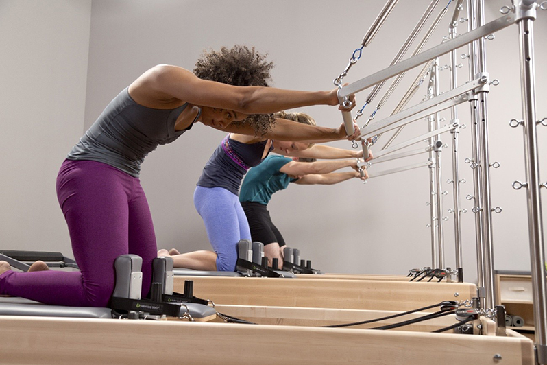 alunos praticando pilates em equipamento cadillac